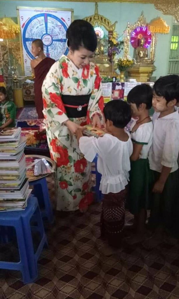 マハトゥカダンパティ寺院で子供へ冊子等を手渡す場面